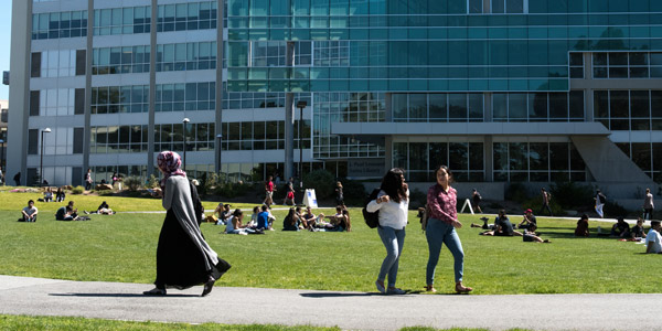 3 students walking in front of library